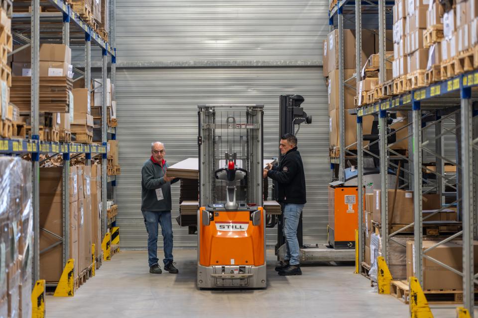 Medewerkers die samenwerken in het magazijn met heftruck