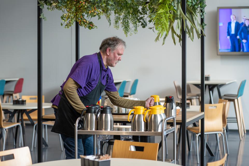 kantinemedewerker zet thermoskannen op tafels
