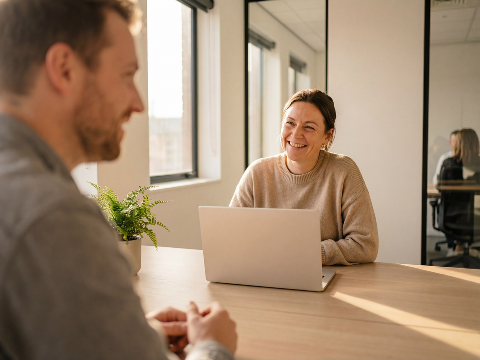 Lachende vrouw aan tafel achter een laptop